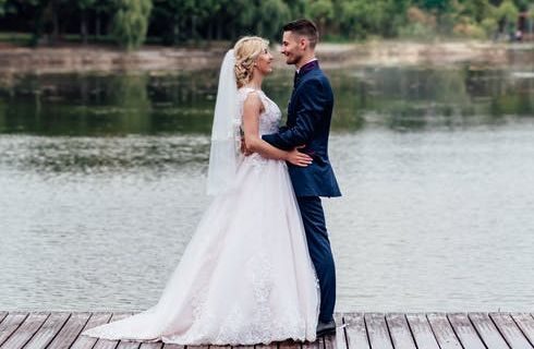 Bride and groom looking at one another on a dock