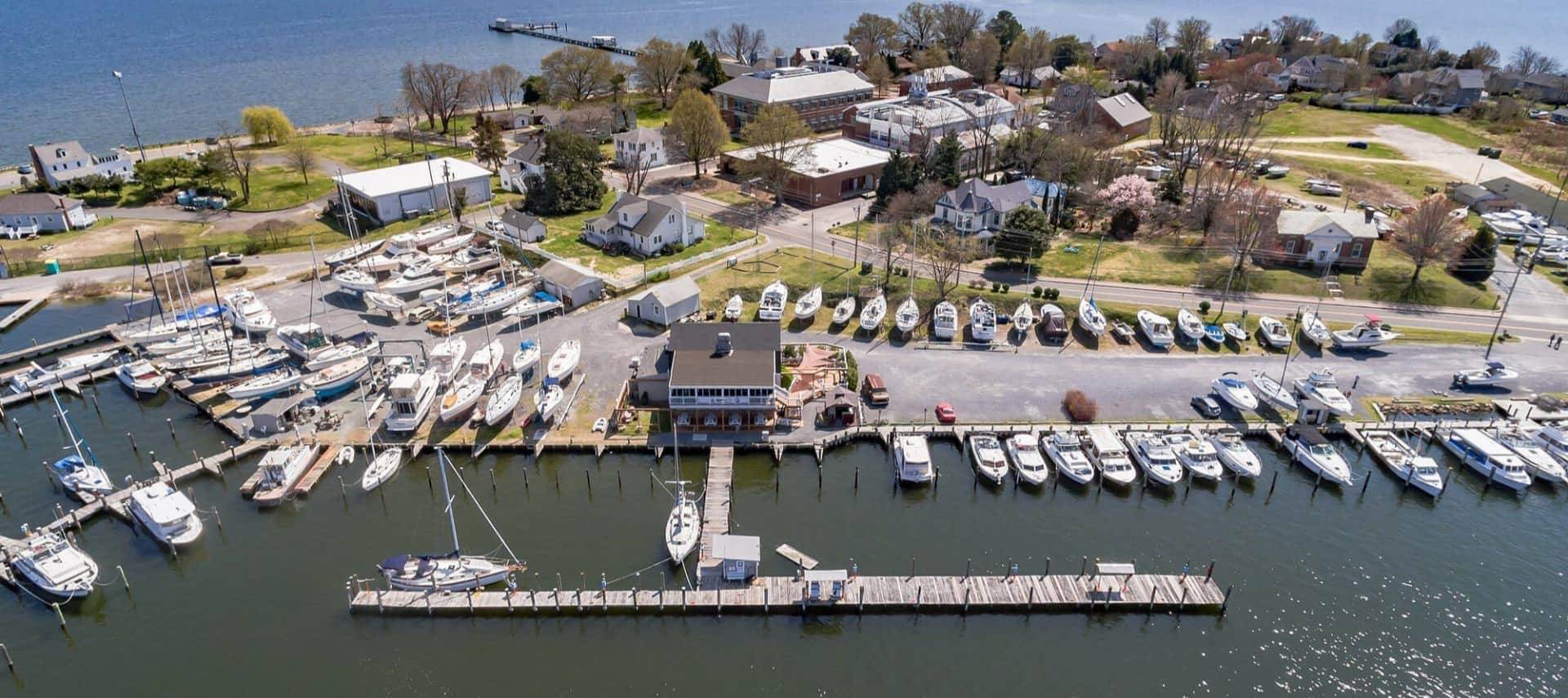 Aerial view of a marina with boats docked at the pier and on land in storage slots